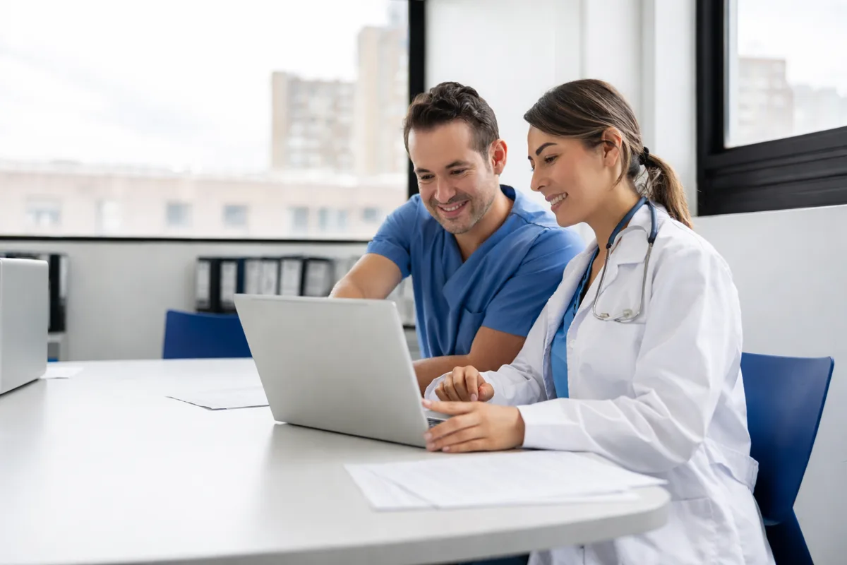 Dos médicos revisando su perfil profesional en una computadora portátil